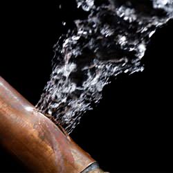 A bursting copper pipe in Eugene, with water gushing out.