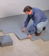 Contractors installing basement subfloor tiles and matting on a concrete basement floor in Bend, Oregon